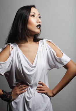 Siyah dudaklı, uzun saçlı, şık beyaz elbiseli güzel Asyalı kadın mankeni.