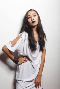 Siyah dudaklı, uzun saçlı, şık beyaz elbiseli güzel Asyalı kadın mankeni.