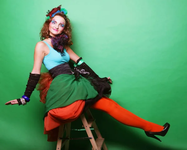 Pretty young woman in a carnival dress sits on a stool, doll style — Stock Photo, Image