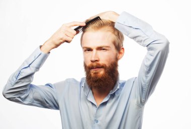 Yakışıklı, gülümseyen genç adam beyaz arka plan üzerinde modern saç stili yapıyor.