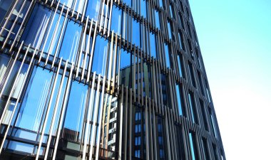 Yazın güneşli bir günde dış cephe inşa eden ofisler. Mavi gökyüzü pencerelerin camına yansımıştı. Gelecekçi iş konsepti.