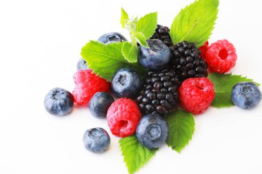 Beyaz zemin üzerinde nane yaprağı olan lezzetli olgun meyveler. Kapat..