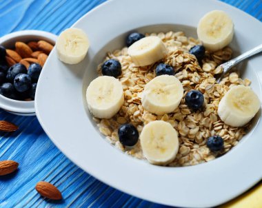 Beyaz tabakta taze böğürtlen ve mavi ahşap arka planda portakal suyu bulunan yulaf ezmesi.