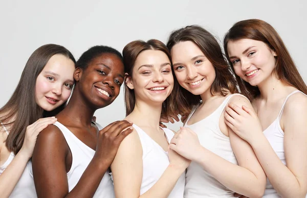 Група з п'яти молодих жінок друзів різних національностей, які обіймаються і посміхаються разом — стокове фото