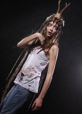 Genç ve güzel bir cadı karanlık arka planda. Parlak makyaj, kafatası - Cadılar Bayramı teması.