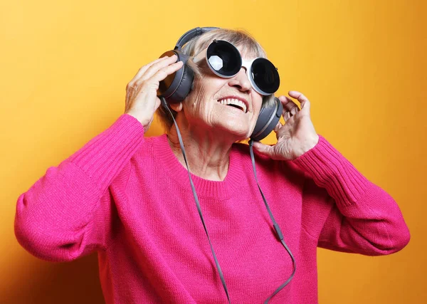 Wesoła starsza kobieta słuchająca muzyki ze słuchawkami na białym tle — Zdjęcie stockowe