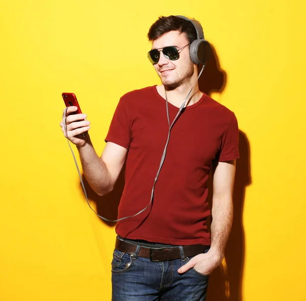 年轻人喜欢用耳机听音乐 听音乐 年轻英俊 头戴太阳镜 背对着黄色背景微笑的男人 — 图库照片