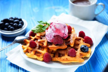 Taze böğürtlenli Belçika waffle 'ları ve ahşap arka planda dondurma. Kapat..