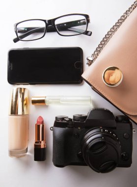 Kozmetik ürünleri, aksesuarlar, kamera ve beyaz arka planda akıllı telefonlu bej renkli kadın çantası. Güzellik ve moda konsepti.