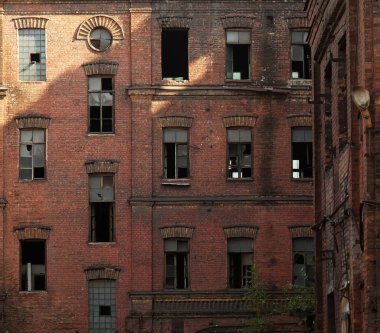 Terk edilmiş bir fabrikanın eski bir binasının camları kırılmış. Yaz günü.