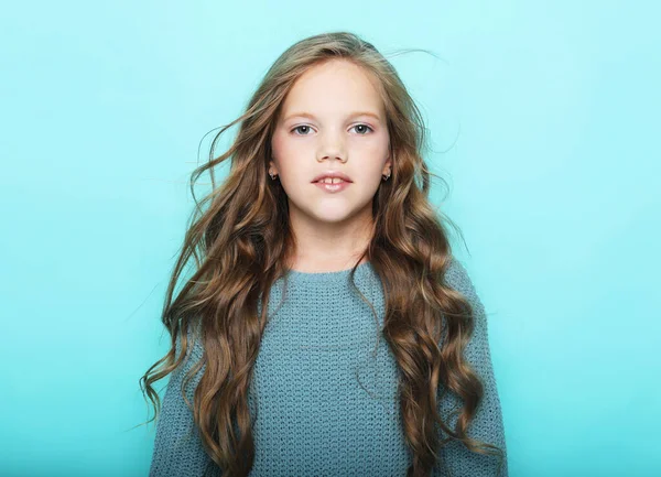 Μικρό κορίτσι με μακριά σγουρά μαλλιά, στούντιο σουτ πάνω από το μπλε φόντο — Φωτογραφία Αρχείου