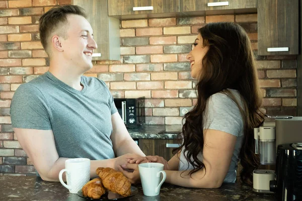 Fiatal pár reggelizik a modern konyhában és beszél, koncepció a boldogság és a mindennapi élet. — Stock Fotó