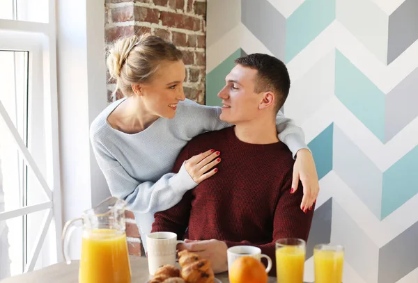 Életmód és emberek koncepció: fiatal boldog pár reggelizni a kora reggeli otthon, ölelés, mosoly. — Stock Fotó