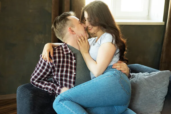 Young beautiful couple is sitting on the couch and hugging. — Stock Photo, Image