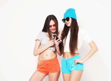 Akıllı telefondan video izleyen ve beyaz arka planda şaşıran bayan arkadaşlar