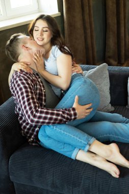 Genç ve güzel bir çift kanepede oturuyor ve sarılıyorlar..