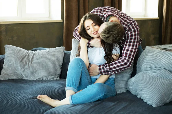 Young beautiful couple is sitting on the couch and hugging. — Stock Photo, Image