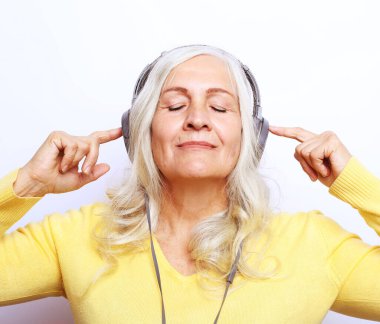 Beyaz arka planda izole edilmiş kulaklıklı, yaşlı, güzel beyaz bir kadının yakın plan fotoğrafı..