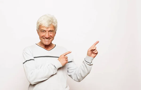 Mutlu ve mutlu bir portre tecrübeli büyükbaba boş bir yeri işaret ederek omuz üstü beyaz süveter — Stok fotoğraf