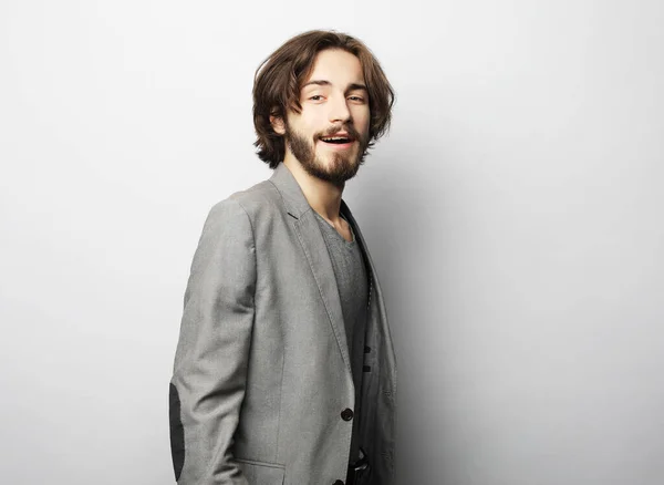 Felice giovane ragazzo barbuto con acconciatura alla moda e barba guardando la fotocamera, sorridente con i denti — Foto Stock