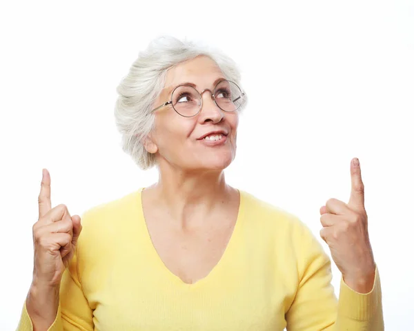 Usmívající se starší šedovlasá žena dáma 60s let ve žlutém ležérní svetr ukazující ukazováček stranou nahoru — Stock fotografie