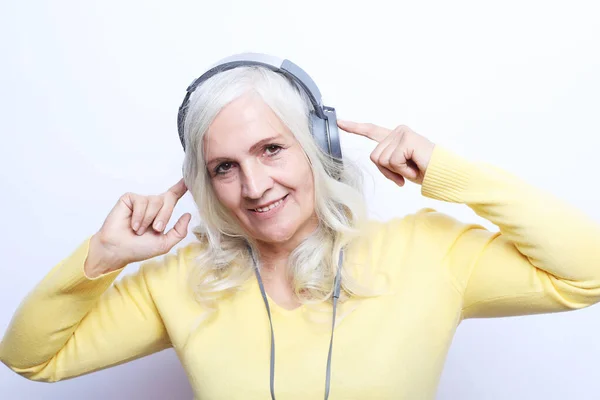 Χαρούμενη ηλικιωμένη γυναίκα που ακούει μουσική με ακουστικά πάνω από λευκό φόντο — Φωτογραφία Αρχείου
