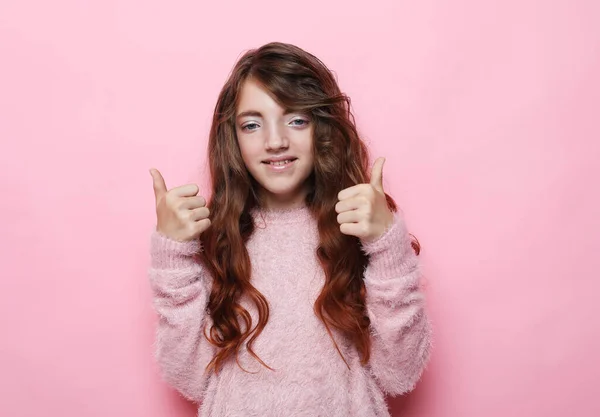 Pessoas, infância e conceito de moda: criança menina vestindo suéter rosa mostrar polegares para cima sobre fundo rosa — Fotografia de Stock