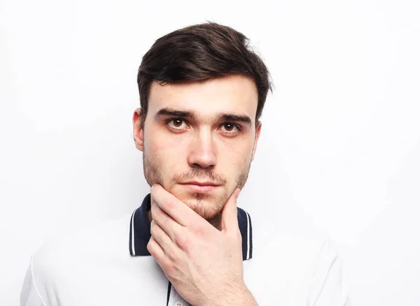 Portrait of a smart young man touches his chin, reflects, making a decision standing against white background — Stock Photo, Image