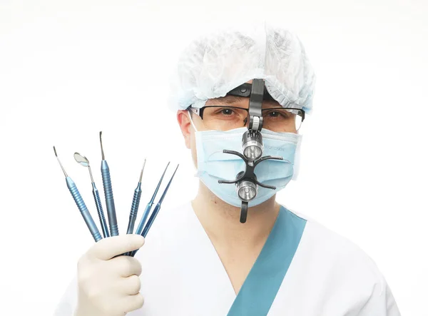 Médico varón con máscara quirúrgica con lupas binoculares e instrumentos dentales de sujeción, aislado sobre fondo blanco. —  Fotos de Stock