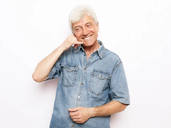 Fénykép idős férfi boldog pozitív mosoly megjelenítése ujj hívás telefon jel felett fehér háttér. — Stock Fotó
