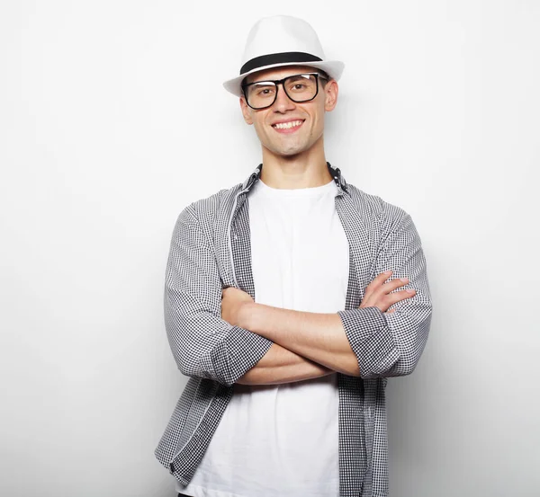 Porträtt av glad leende ung man bär glasögon, ahd hatt med armen korsad — Stockfoto