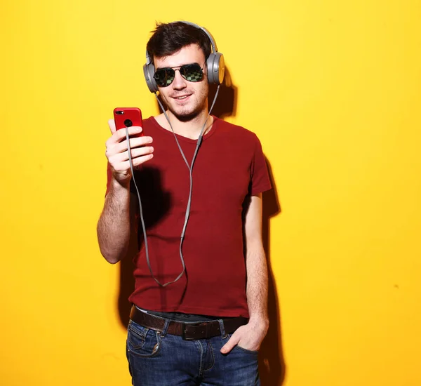 Gelukkige jongeman met koptelefoon. Muziek luisteren over gele backgrund. — Stockfoto