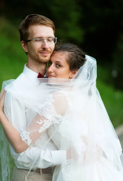 Una giovane sposa e lo sposo in piedi insieme e abbracciare all'aperto — Foto Stock