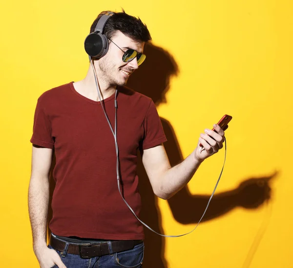 Boldog fiatalember fülhallgatóval. Zene hallgatása sárga háttérben. — Stock Fotó