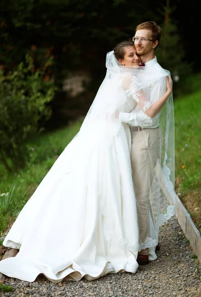 Uma jovem noiva e noivo de pé juntos e abraçar ao ar livre — Fotografia de Stock