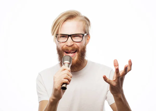 Imagen de un hombre guapo cantando al micrófono. Retrato emocional de un chico atractivo con barba sobre fondo blanco — Foto de Stock