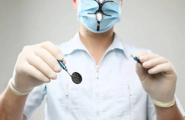 Dentista macho con herramientas de odontología aisladas sobre fondo gris —  Fotos de Stock