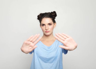 Vücut dili. Stüdyo duvarında poz veren sinirli, genç esmer bir kadın..