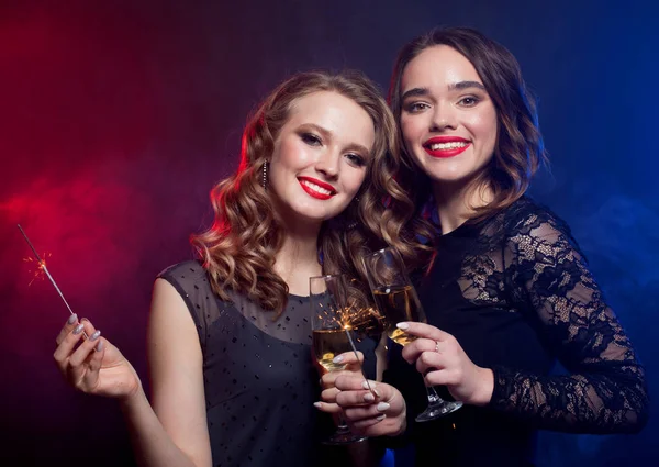 Koncepcja imprezy i ludzi - młode kobiety brzęczące flety z musującym winem na ciemnym tle. — Zdjęcie stockowe