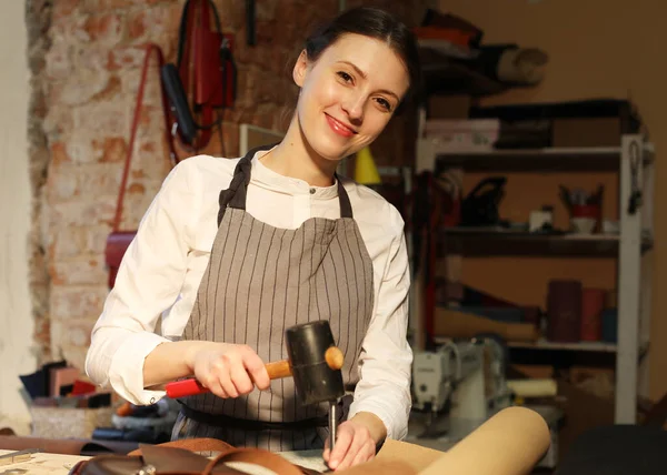 Jeune femme travaille dans un atelier, coud des sacs en cuir — Photo