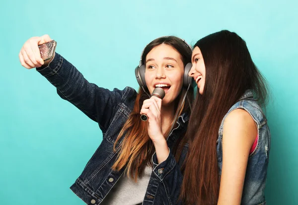 Спосіб життя, щастя, емоції та концепція людей: красиві підлітки хіпстер з мікрофоном співають і фотографують зі смартфоном — стокове фото