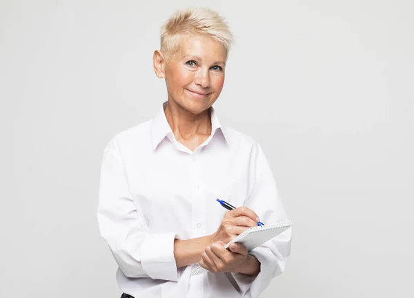 Old people, lifestyle and education concept: Photo portrait of smiling senior female teacher writing notes in organizer — Stock Photo, Image