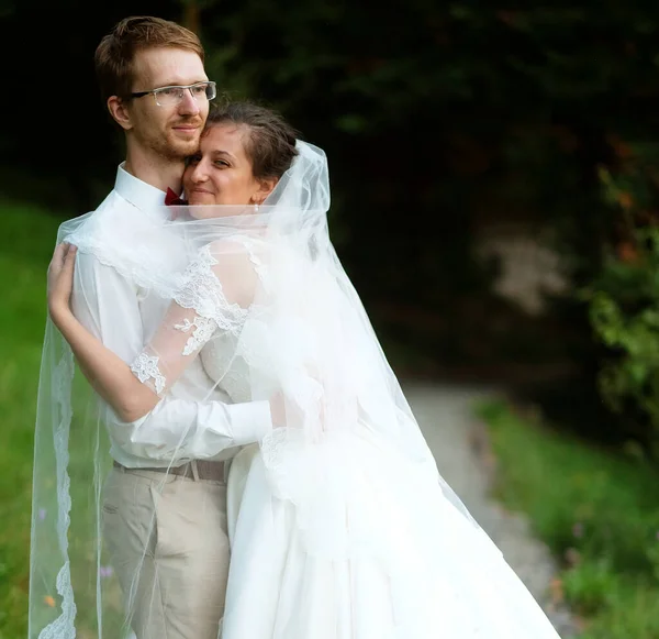 Una giovane sposa e lo sposo in piedi insieme e abbracciare all'aperto — Foto Stock