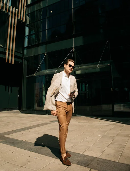 Negócios, pessoas e conceito de sucesso: Homem bonito em roupa fashinable andando perto do escritório moderno — Fotografia de Stock