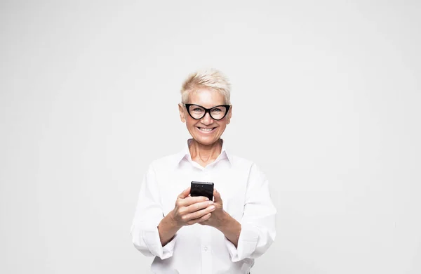 Ganska senior kvinna i casual outfit med modern smartphone — Stockfoto