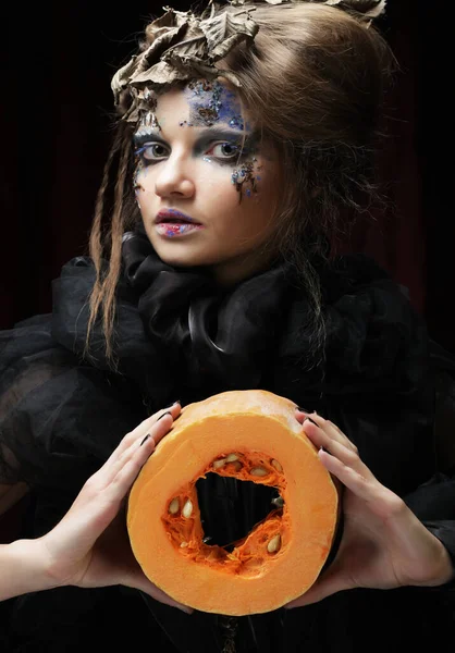 Νεαρή όμορφη γυναίκα σε ένα κοστούμι μάγισσα με φωτεινό μακιγιάζ και χτένισμα κρατώντας μια κολοκύθα, ένα σύμβολο του Χάλογουιν. Πάρτι. Διακοπές. Καρναβάλι. — Φωτογραφία Αρχείου