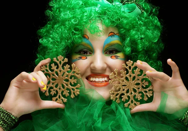 Bella donna con luminoso creativo make up e parrucca verde tenendo fiocchi di neve su sfondo nero — Foto Stock
