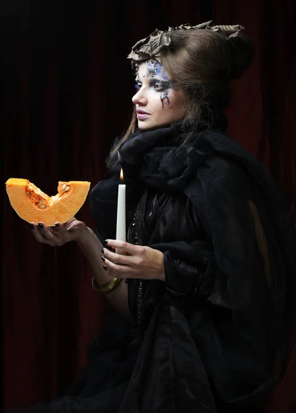 Młoda piękna kobieta w stroju czarownicy z jasnym makijażem i fryzurą trzymając dynię, symbol halloween. Impreza. Wakacje. Karnawał. — Zdjęcie stockowe