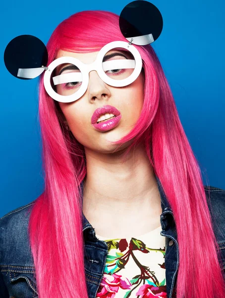 Young fashionable woman with pink hair and big sunglasses over blue background — Stock Photo, Image