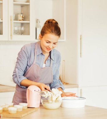 Genç kadın pasta şefi kremayla çalışıyor. Lezzetli hamur işleri. Hobi olarak. Küçük ev işleri..